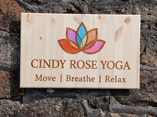 Laser engraved pine business logo sign with colour-filled artwork on a stone wall, Moon Groves Devon — MoonGroves.com